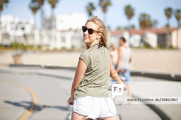 Junge Radfahrerin schaut sich beim Radfahren am Venice Beach in Venice Beach  Los Angeles  Kalifornien  USA  über die Schulter