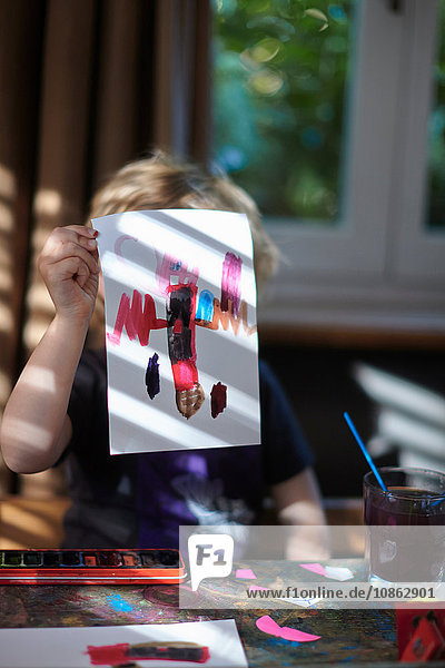 Portrait of girl holding up painting in front of her