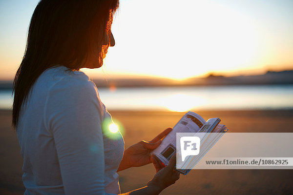 Frau liest Buch am Cannon Beach bei Sonnenuntergang  Kalifornien  USA
