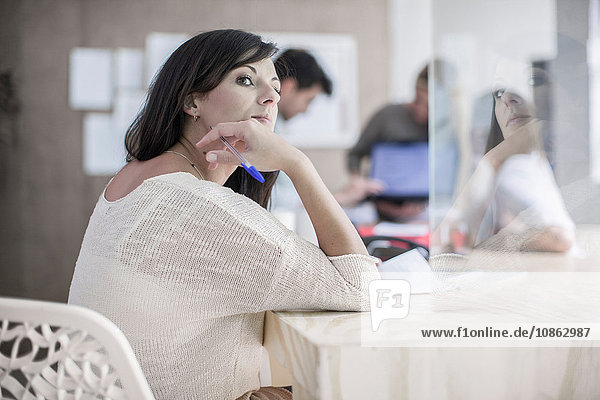 Female designer daydreaming at desk in design studio