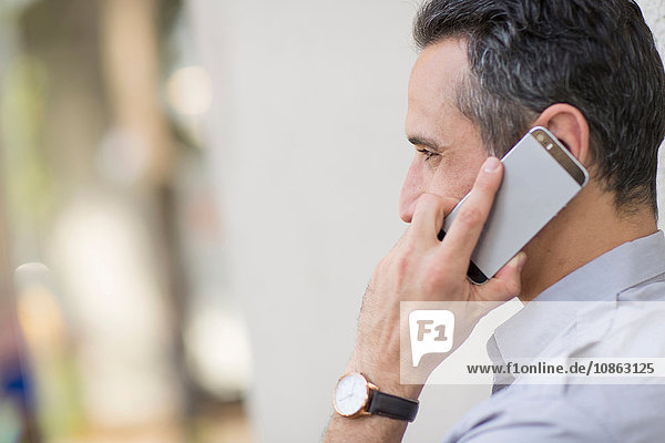 Side view of man using smartphone to make telephone call
