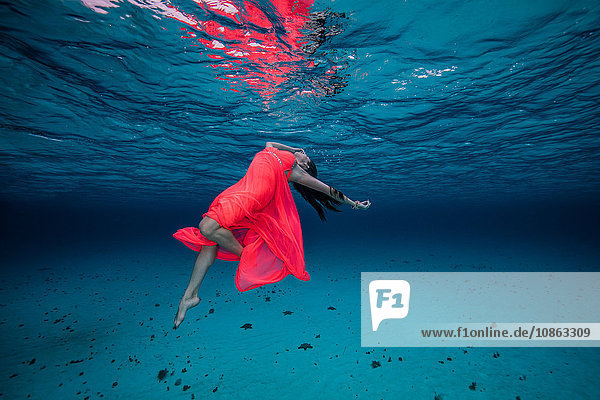 Frau unter Wasser in rotem Kleid