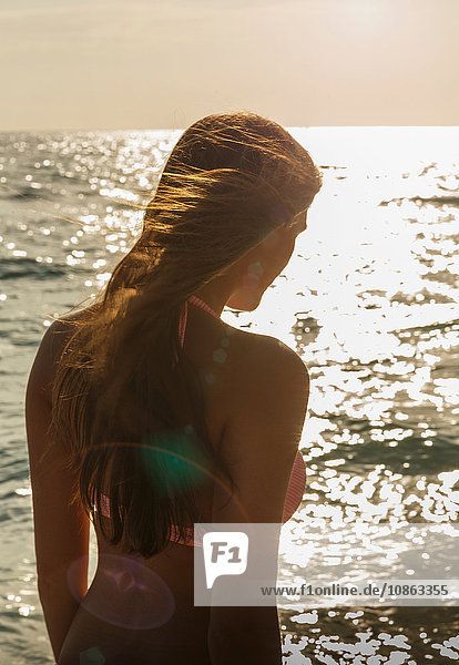Silhouettierte,  sonnenbeschienene Rückansicht einer jungen Frau am Strand von Miami,  Florida,  USA