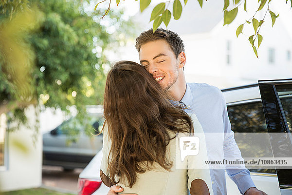 Young business couple kissing on street before leaving in car
