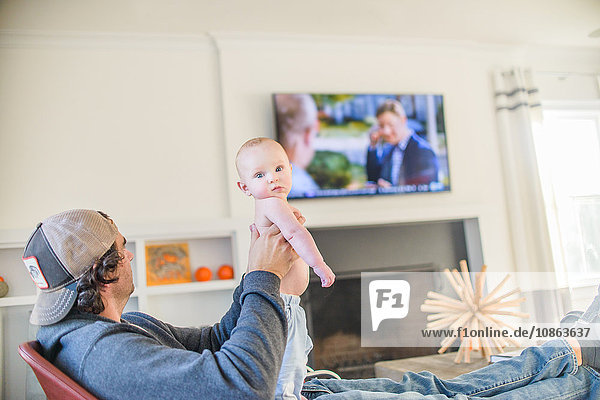 Father watching television holding baby boy