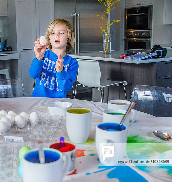 Boy in kitchen decorating eggs for Easter