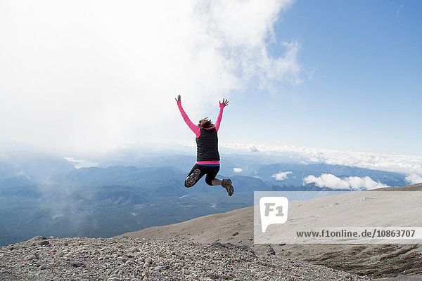 Young woman at mountain top  jumping fro joy  rear view  Mt. St. Helens  Oregon  USA