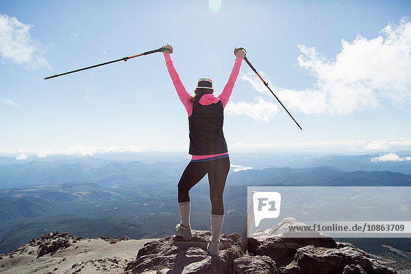 Junge Frau auf dem Berggipfel  die Wanderstöcke in der Luft hält  Rückansicht  Mt. St. Helens  Oregon  USA