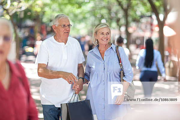 Älterer Mann und Frau halten beim Einkaufen in der Stadt Händchen