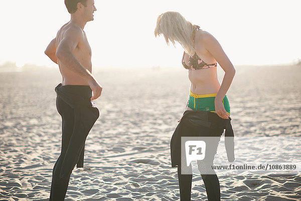 Surfing couple putting on wetsuits on Venice Beach  California  USA