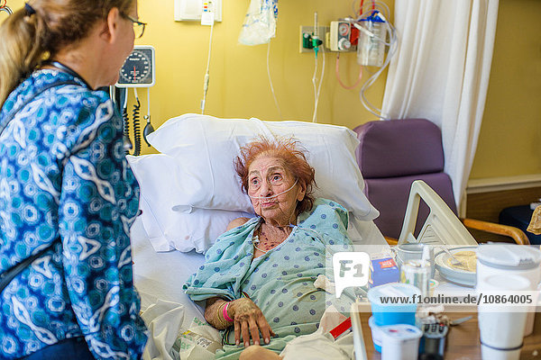 Patient im Krankenhausbett im Gespräch mit Besucher