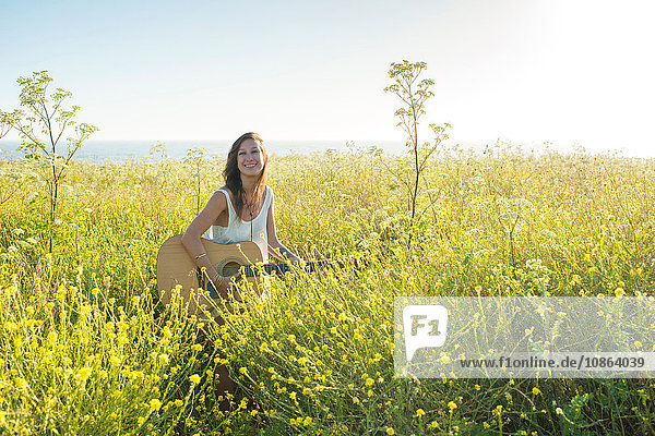 Frau mit Gitarre im Feld der Wildblumen