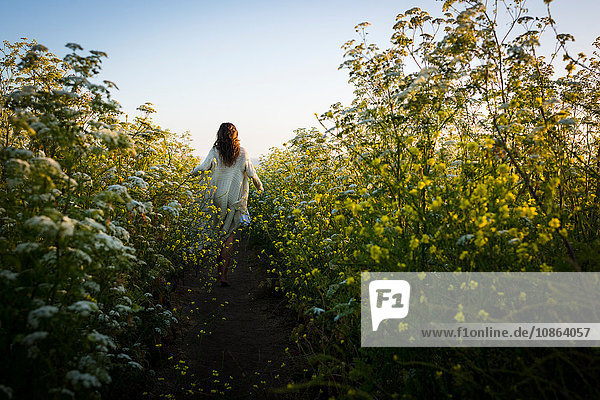 Frau geht durch ein Feld mit Wildblumen