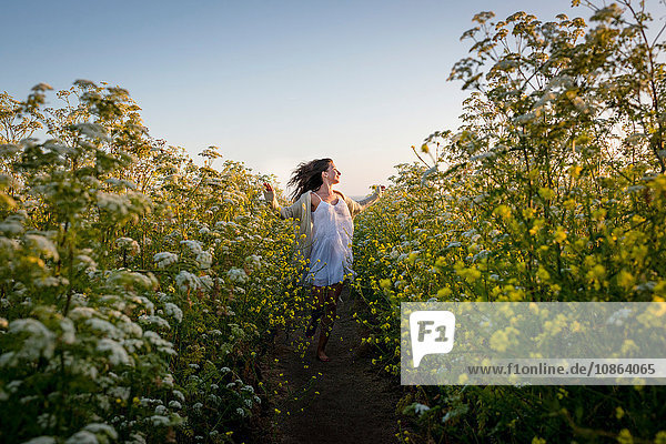 Frau geht durch ein Feld mit Wildblumen