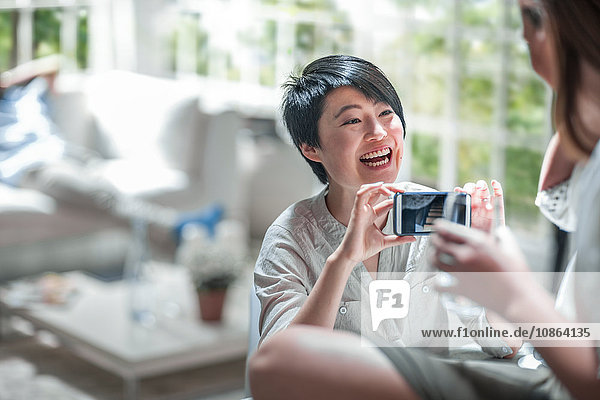 Frau zeigt einem Freund ein Foto im Smartphone