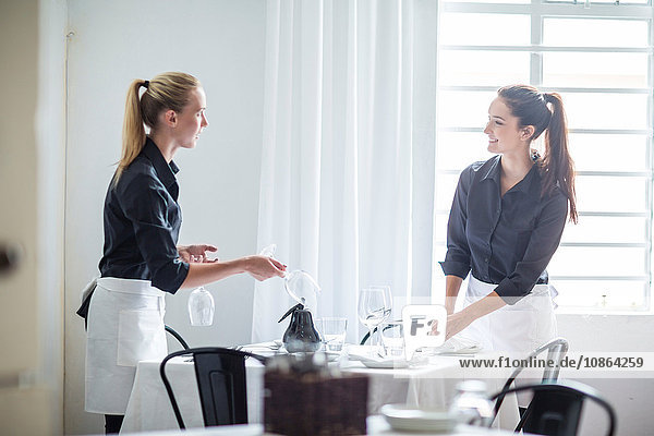 Waitresses chatting and setting table in restaurant