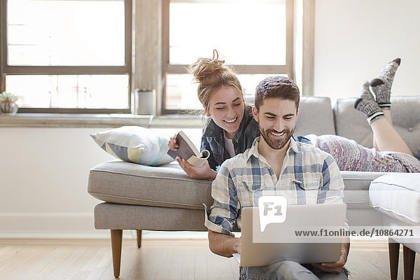 Young couple relaxing at home  looking at laptop