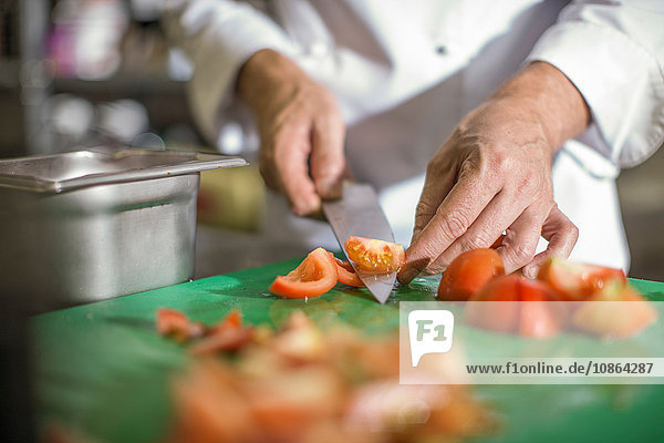 Chef slicing tomatoes on table