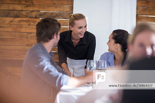 Kellnerin im Gespräch mit Kunden im Restaurant