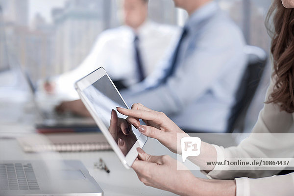 Geschäftsfrauen mit digitalem Tablet im Büro  Kollegen arbeiten im Hintergrund
