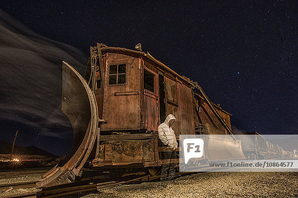 Gespenstischer Mann mit Kapuze steht an verlassenem alten Zug