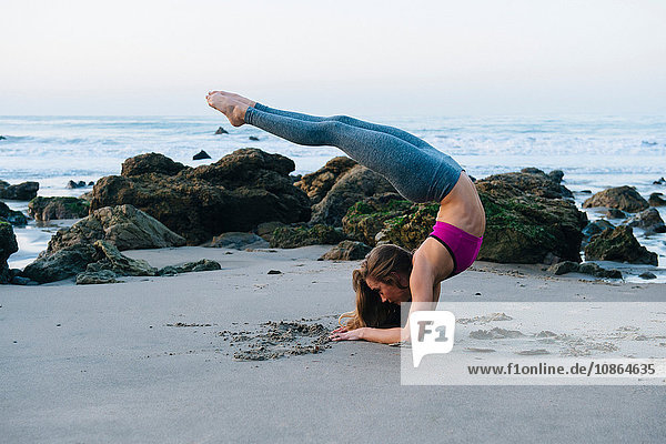 Junge Frau beugt sich nach hinten und praktiziert Yoga-Pose am Strand  Los Angeles  Kalifornien  USA