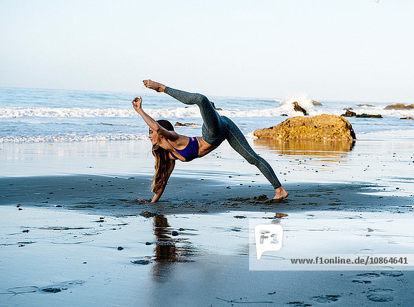 Young female dancer balancing on hand at beach  Los Angeles  California  USA