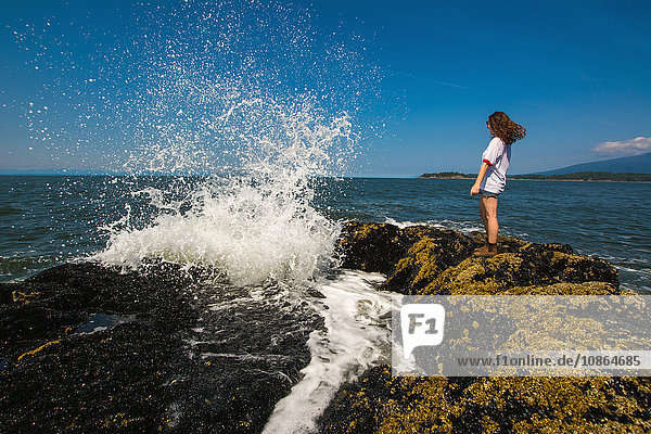 Junge Frau steht auf Felsen am Ozean  Bowen Island  Britisch-Kolumbien  Kanada