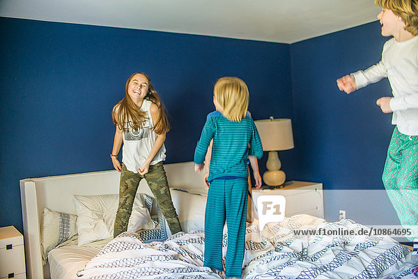 Teenager-Mädchen springt mit jüngeren Brüdern ins Bett