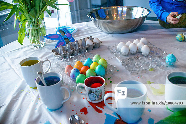 Schnappschuss eines Jungen  der zu Ostern bei Tisch Eier färbt
