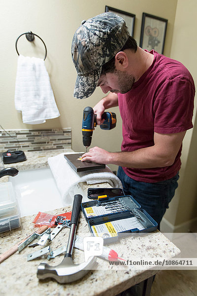 Mann bohrt Fliesen zur Reparatur des Badezimmers