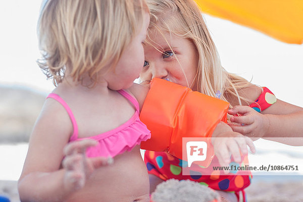 Girl inflating toddler sister's inflatable armband on beach  Cape Town  South Africa
