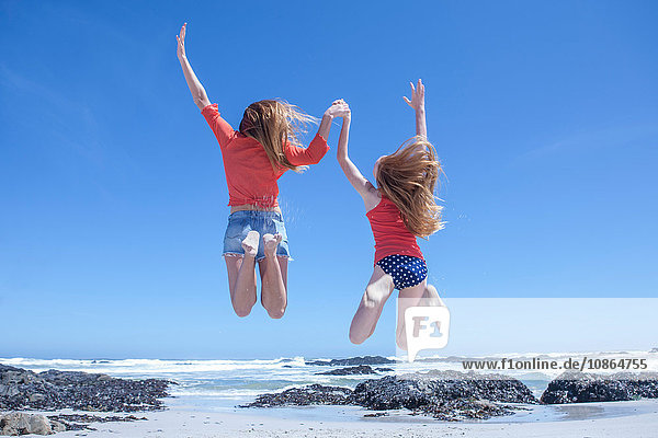 Mädchen und junge Frau springen am Strand in die Luft  Kapstadt  Südafrika