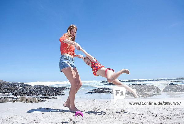 Junge Frau hält und dreht Mädchen am Strand  Kapstadt  Südafrika