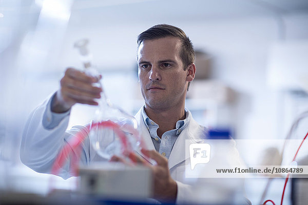 Mittelgroßer erwachsener Mann im Labor  hält Reagenzglas