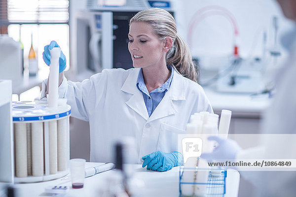 Mittlere erwachsene Frau im Labor beim Einführen des Reagenzröhrchens in die Schale