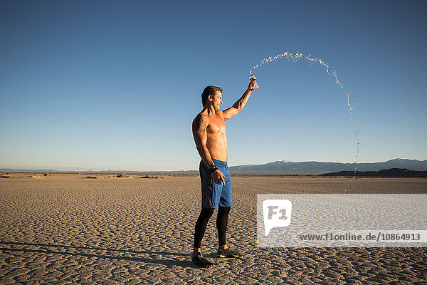 Männertraining  Spritzen einer Wasserflasche auf den trockenen Seeboden  El Mirage  Kalifornien  USA