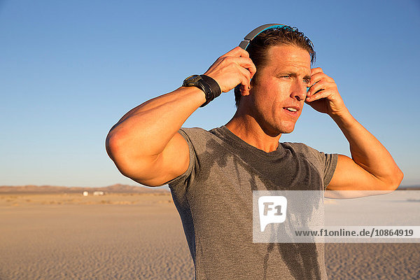 Männertraining  Aufsetzen von Kopfhörern auf trockenem Seeboden  El Mirage  Kalifornien  USA