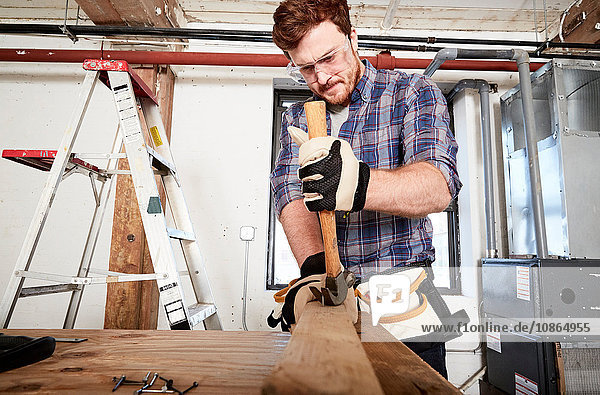 Zimmermann in der Werkstatt beim Entfernen von Nägeln aus Holz mit dem Hammer