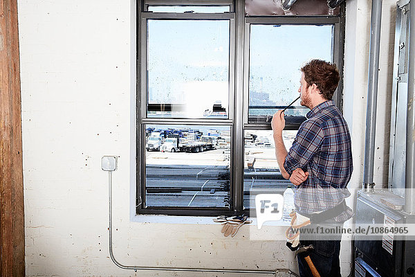 Zimmermann  der aus dem Fenster schaut und denkt