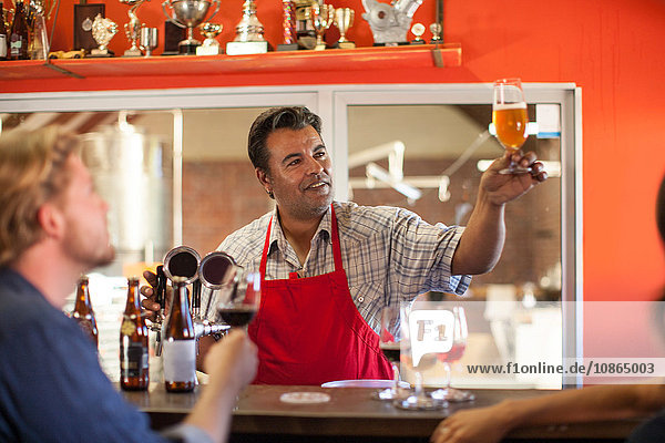 Barkeeper in Gaststätte hält Bierglas lächelnd in der Hand