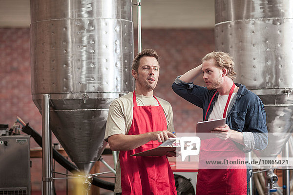Colleagues in microbrewery holding clipboards and digital tablets