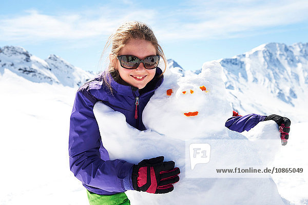Porträt eines jugendlichen Mädchens  das einen Schneemann umarmt