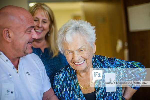 Grauhaarige Frau mit lachenden Freunden