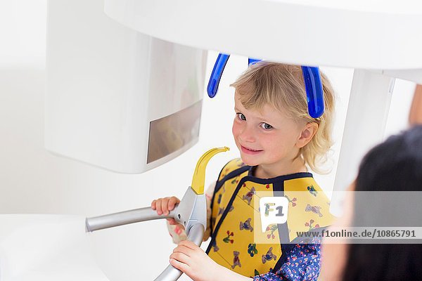High angle view of girl in x-ray machine having dental examination smiling