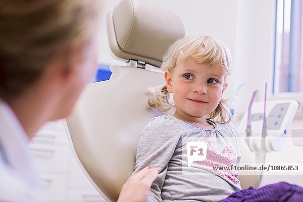 Worried looking girl in dentist chair chatting with dentist