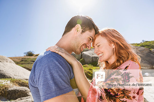 Couple hugging outdoors face to face laughing