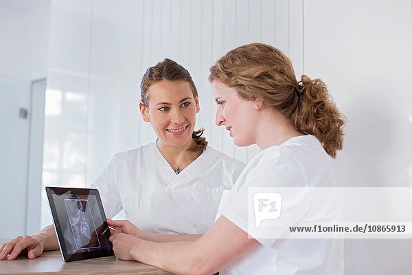 Dentists looking at digital tablet with x-ray image on screen  smiling