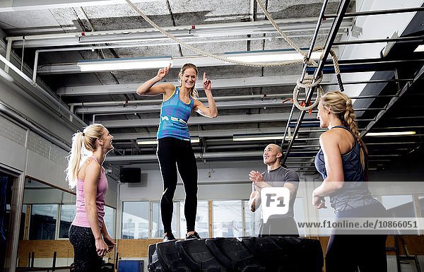 Weibliche Crossfitterin springt auf Reifenstapel in Turnhalle