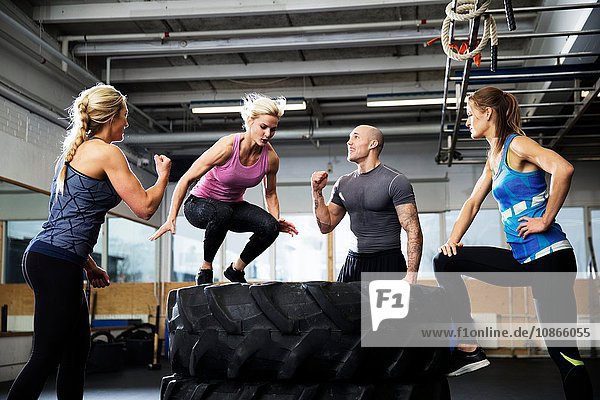 Woman crossfitter jumping on tyre stack in gym